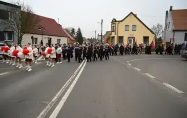widzimy idące po ulicy dziewczyny z pomponami a za nimi idzie orkiestra oraz sztandary