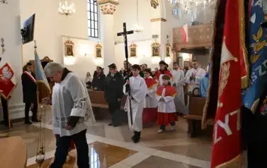 widzimy dużą ilość oso&oacute;b w kościele oraz idących ministrant&oacute;w z krzyżem