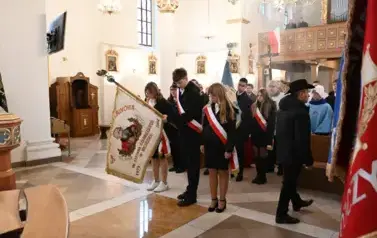 widzimy dużą ilość oso&oacute;b w kościele oraz idące osoby ze sztandarami