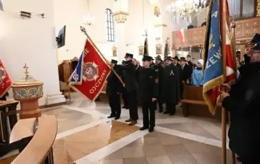 widzimy dużą ilość oso&oacute;b w kościele oraz idące osoby ze sztandarami