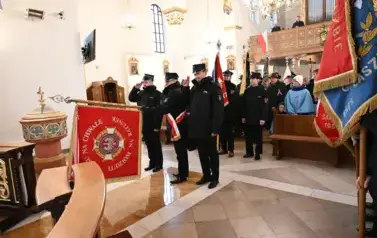 widzimy dużą ilość oso&oacute;b w kościele oraz idące osoby ze sztandarami