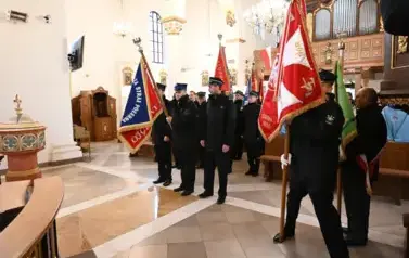 widzimy dużą ilość oso&oacute;b w kościele oraz idące osoby ze sztandarami