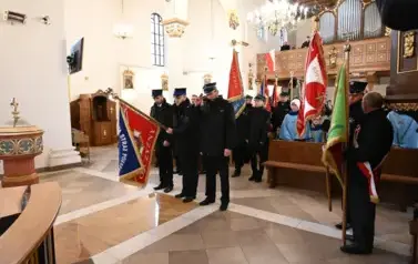 widzimy dużą ilość oso&oacute;b w kościele oraz idące osoby ze sztandarami