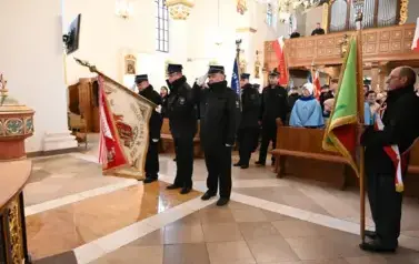 widzimy dużą ilość oso&oacute;b w kościele oraz idące osoby ze sztandarami