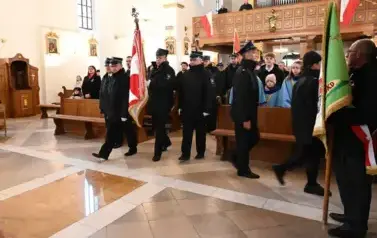 widzimy dużą ilość oso&oacute;b w kościele oraz idące osoby ze sztandarami