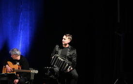 widzimy pana grającego na gitarze oraz drugiego pana grającego na akordeonie 