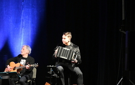 widzimy pana grającego na gitarze oraz drugiego pana grającego na akordeonie 