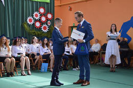 Na zdjęciu widać jak w&oacute;jt wręcza nagrodę najlepszemu uczniowi w szkole. Ubrani są w granatowe garnitury.