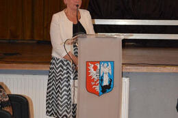 NA zdjęciu widać przemawiającą była dyrektor szkoły podstawowej w Miescisku. Kobieta stoi za m&oacute;wnicą z herbem Gminy Mieścisko.