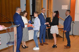 Na zdjęciu pani dyrektor gratuluje chłopcu stypendium. Pan w&oacute;jt natomiast przekazuje gratulacje jego rodzicom.