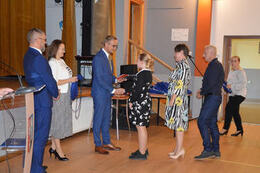 Na zdjęciu w&oacute;jt wręcza stypendium dziewczynce. Obok stoją jej rodzice.