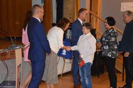 Na zdjęciu pani dyrektor gratuluje dobrych wynik&oacute;w chłopcu. Za nimi rodzice dziecka odbierają gratulacje od w&oacute;jta.