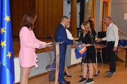 Na zdjęciu widać jak dziewczynka otrzymła stypendium naukowe od W&oacute;jta Gminy Mieścisko. Przyjmuje teraz gratulacje od radnego.