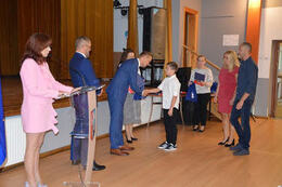 Na zdjęciu w&oacute;jt Gminy Mieśicsko wręcza stypendium chłopcu. Obok W&oacute;jta stoją dyrektor szkoły i radny. Obok chłopca znajdują sie jego rodzice.