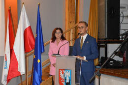 Na zdjęciu widać przemawiającego W&oacute;jta Gminy Mieścisko. Ubrany jest w granatowy garnitur. Przemawia przy m&oacute;wnicy z herbem Gminy Mieścisko.