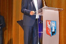 Zdjęcie przedstawia przemawiającego mężczyznę ubranego w granatowy garnitur.