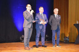 Na zdjęciu widać trzech elegancko ubranych mężczyzn znajdujących się na scenie.