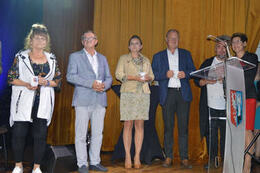 Na zdjęciu widać ludzi stojących na scenie. W rękach trzymają kubki.