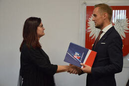 Na zdjęciu w&oacute;jt Gminy Mieścisko wręcza nagrodę nauczycielce w ciemnej sukni. Ma ona okulary i ciemne, p&oacute;łdługie włosy.