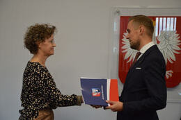 Na zdjęciu w&oacute;jt Gminy Mieścisko wręcza nagrodę nauczycielce w kr&oacute;tkich włosach. Ma ona okulary i ubrana jest w wzorzystą bluzkę i jasne spodnie.