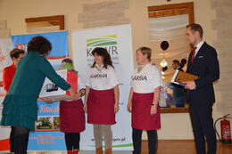 Na zdjęciu widać jak członkini komisji i w&oacute;jt wręczają nagrody uczestniczką z Sarbii.