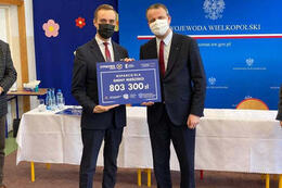 Na zdjęciu widać z lewej strony w&oacute;jta gminy Mieścisko a z prawej strony wojewode wielkopolskiego. Oboje ubrani są w garnitury i trzymają tabliczkę z kwotą na Granty PPGR.