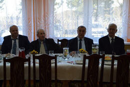 Zdjęcie przedstawia czterech mężczyzn w garniturach, siedzących przy stole.