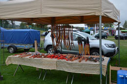 Zdjęcie przedstawia stragan z drewnianymi mieczami, toporami i innymi przedmiotami wojennymi wykonanymi z drewna.