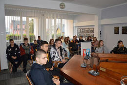 Zdjęcie przedstawia grupę młodzieży siedzącą na krzesłach w sali sesyjnej. Są to zar&oacute;wno dziewczyny jak i chłopacy.