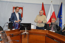 Zdjęcie przedstawia przemawiającego starszego Niemca. Z lewej strony stoi W&oacute;jt Gminy Mieścisko, z prawej strony siedzi drugi starszy mężczyzna.