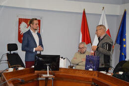 Zdjęcie przedstawia rozmowę w&oacute;jta z przedstawicielem delegacji z Niemiec. Gość przemawia do włodarza, w ręce trzyma podarunek.