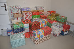 Zdjęcie przedstawia prezenty poukładane jeden na drugim. Opakowane są w kolorowe papiery.