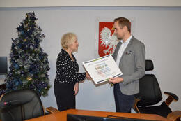 Zdjęcie przedstawia W&oacute;jta wręczajającego symboliczną premesę zwycięzcy projektu rejonowego. Jest to kobieta w czarno-białej koszuli i czarnej sp&oacute;dnicy.