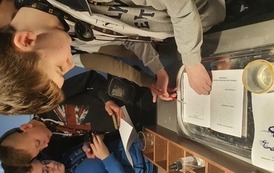 Zdjęcie przedstwia dzieci wykonujących eksperyment.