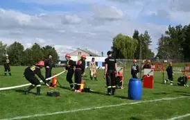 Młodzieżowa drużyna strażacka wykonuję zadanie konkurencyjne trafiając wężem z wodą do tarczy nalewowej