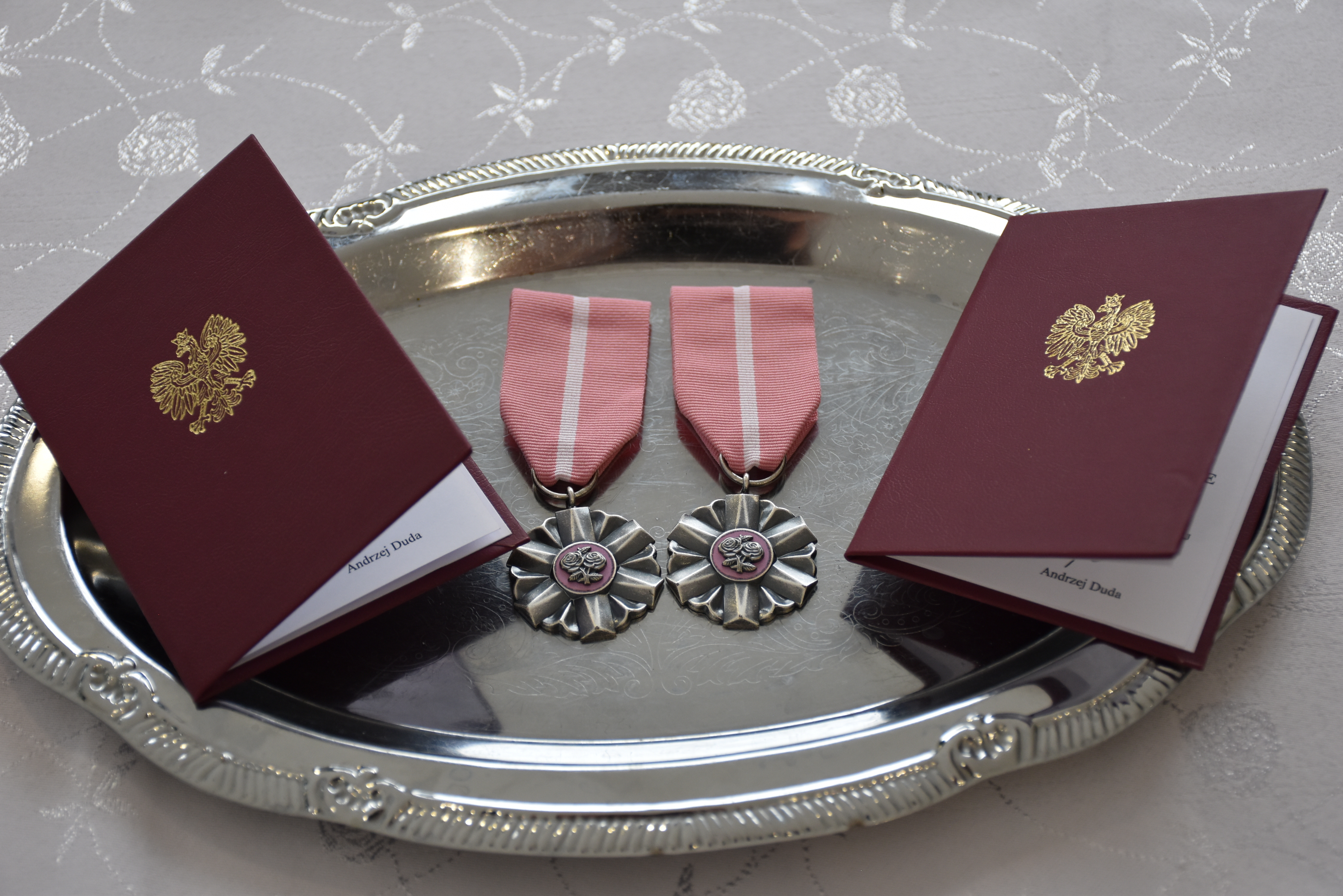 medale za długoletnie pożycie małżeńskie wyłożone na&nbsp;srebrnej tacy