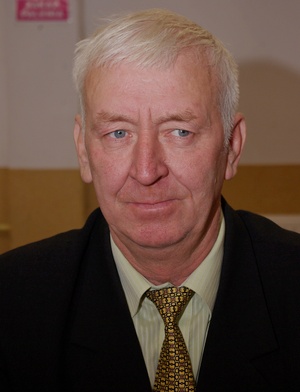 Zdjęcie przedstawia portret Radnego Mariana Wituckiego. Starszy mężczyana ma siwe włosy. Ubrany jest w jasną koszulę, krawat oraz ciemną marynarkę.